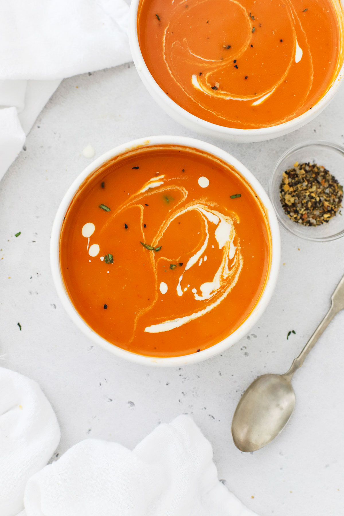 gluten free tomato soup in a white bowl with a drizzle of cream
