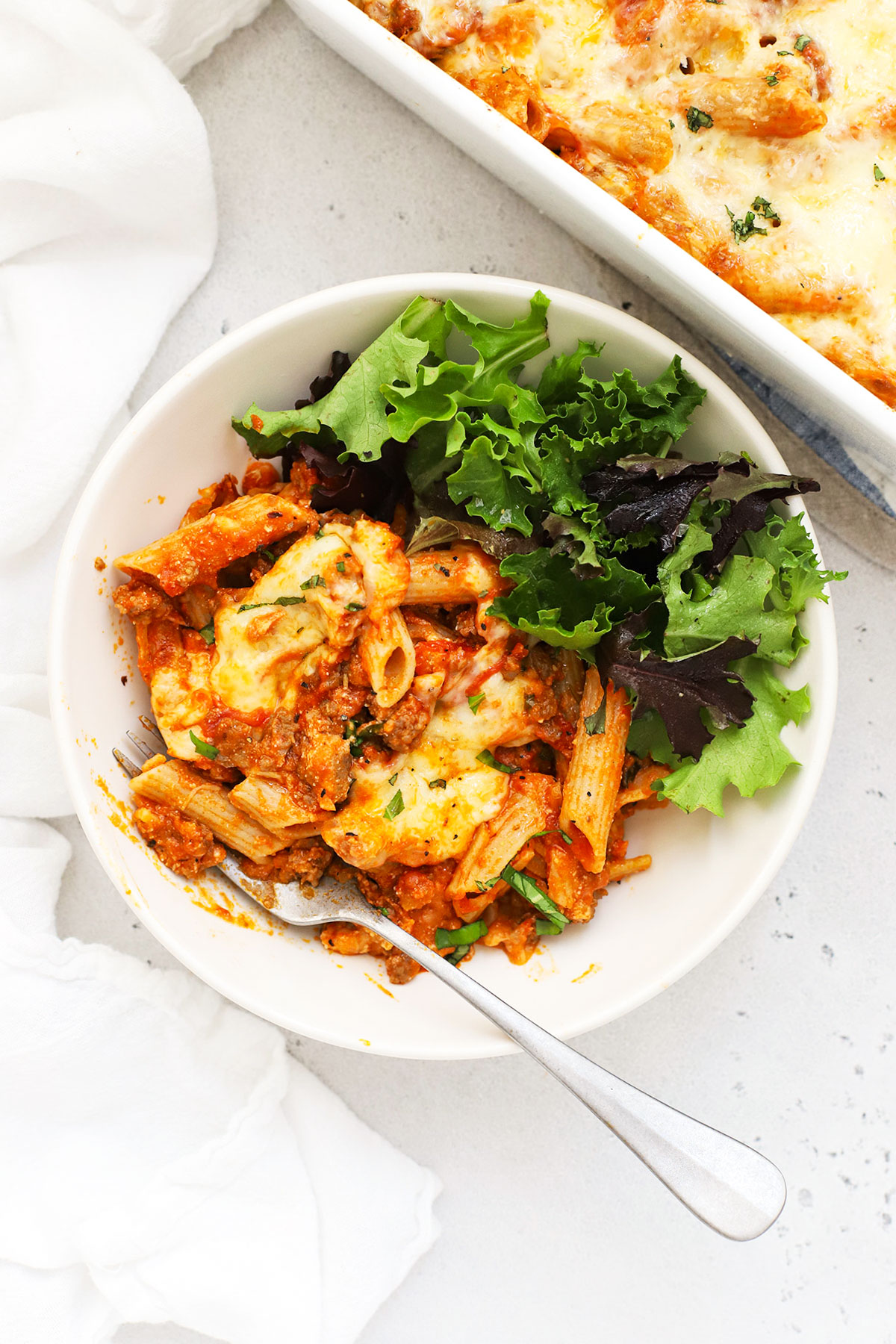 gluten-free baked ziti on a plate with a green side salad