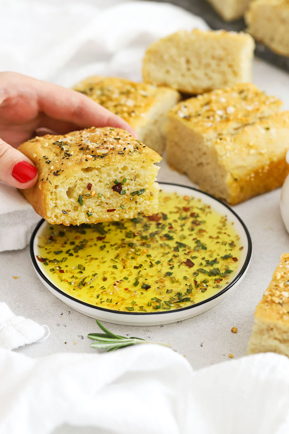a slice of gluten-free focaccia being dipped into dipping oil