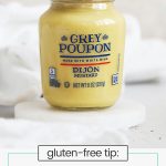 a bottle of Grey Poupon dijon mustard on a white background
