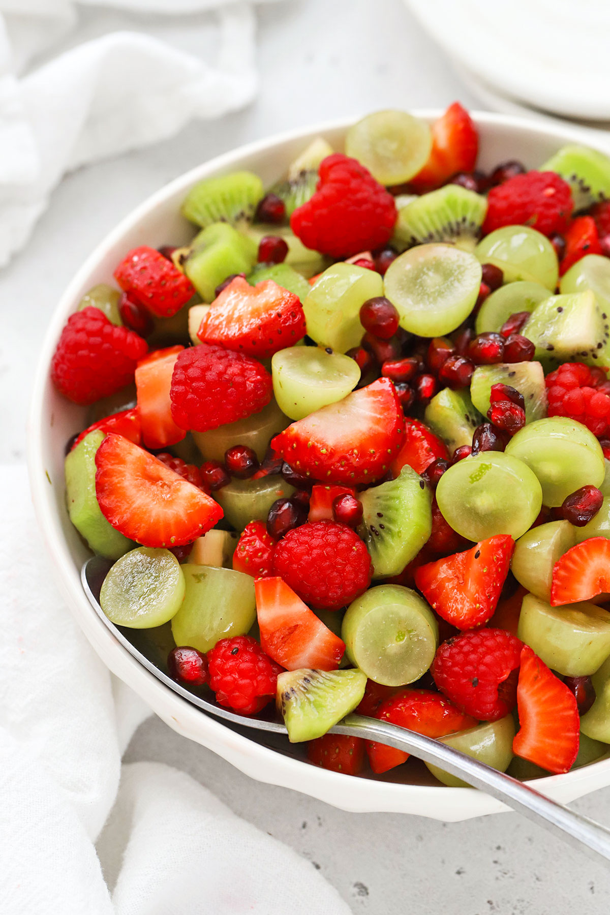 red and green fruit salad in a white serving bowl