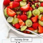 red and green fruit salad in a white serving bowl