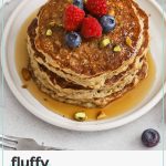 gluten-free oatmeal pancakes stacked on a white plate, topped with fresh berries and maple syrup