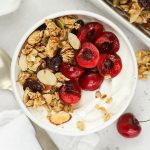 gluten-free cherry granola sprinkled on vanilla yogurt with cherries