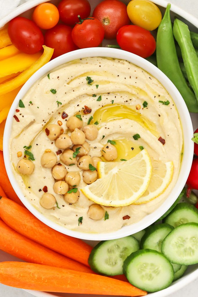 lemon hummus in a bowl surrounded by colorful veggies