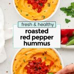 Homemade red pepper hummus in a white bowl with fresh veggies