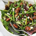 roasted asparagus salad with pecans, cranberries, and feta cheese in a white serving bowl
