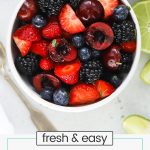 small white bowl of cherry berry fruit salad with honey lime dressing