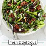 roasted asparagus salad with pecans, cranberries, and feta cheese in a white serving bowl