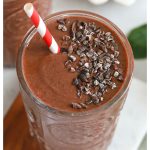 two chocolate cherry smoothies with bowls of frozen cherries and cacao nibs in the background