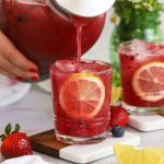 pouring honey berry lemonade into a short glass