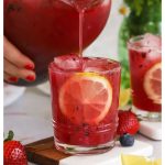 pouring honey berry lemonade into a short glass