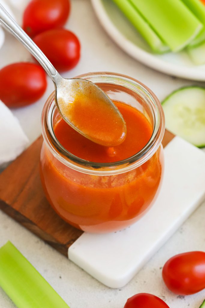 spoon scooping homemade gluten-free buffalo sauce out of a jar