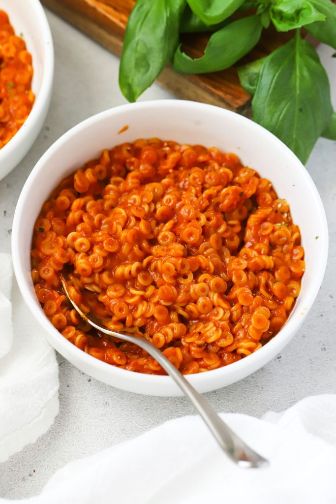 Bowls of gluten-free spaghettios next to fresh basil