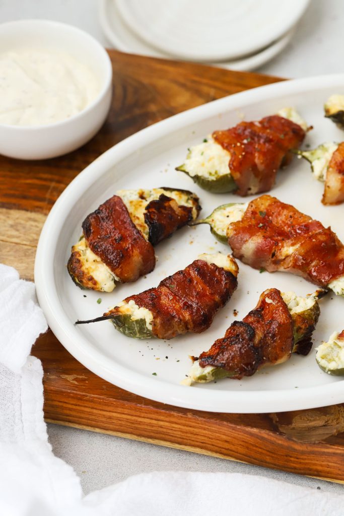 a plate of bacon-wrapped jalapeño poppers with pineapple cream cheese filling