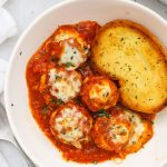 Gluten-free chicken parmesan meatballs in marinara with a slice of gluten-free garlic bread