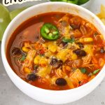 A bowl of cheesy chicken enchilada soup garnished with cilantro and sliced jalapeño