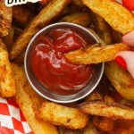 Dipping a golden brown french fry in ketchup