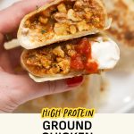 Holding a ground chicken burrito topped with salsa and lime crema