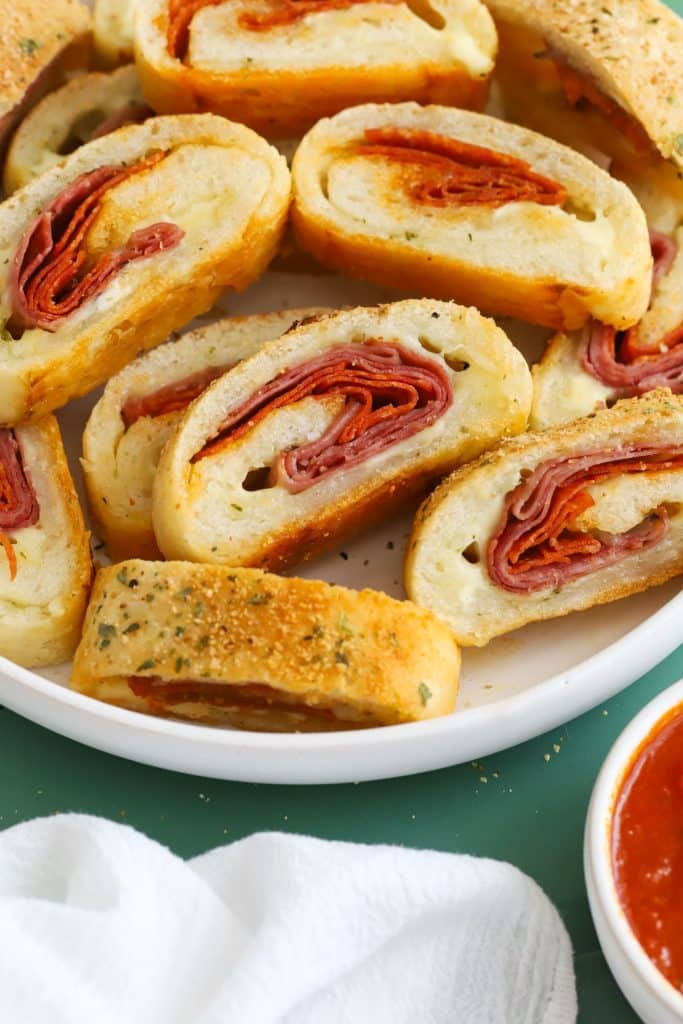 A white serving platter of gluten-free stromboli filled with deli meats and mozzarella cheese