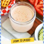 A jar of burger sauce surrounded by burger toppings and a basket of waffle fries