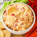 A cracker dipped into a bowl of homemade pimento cheese