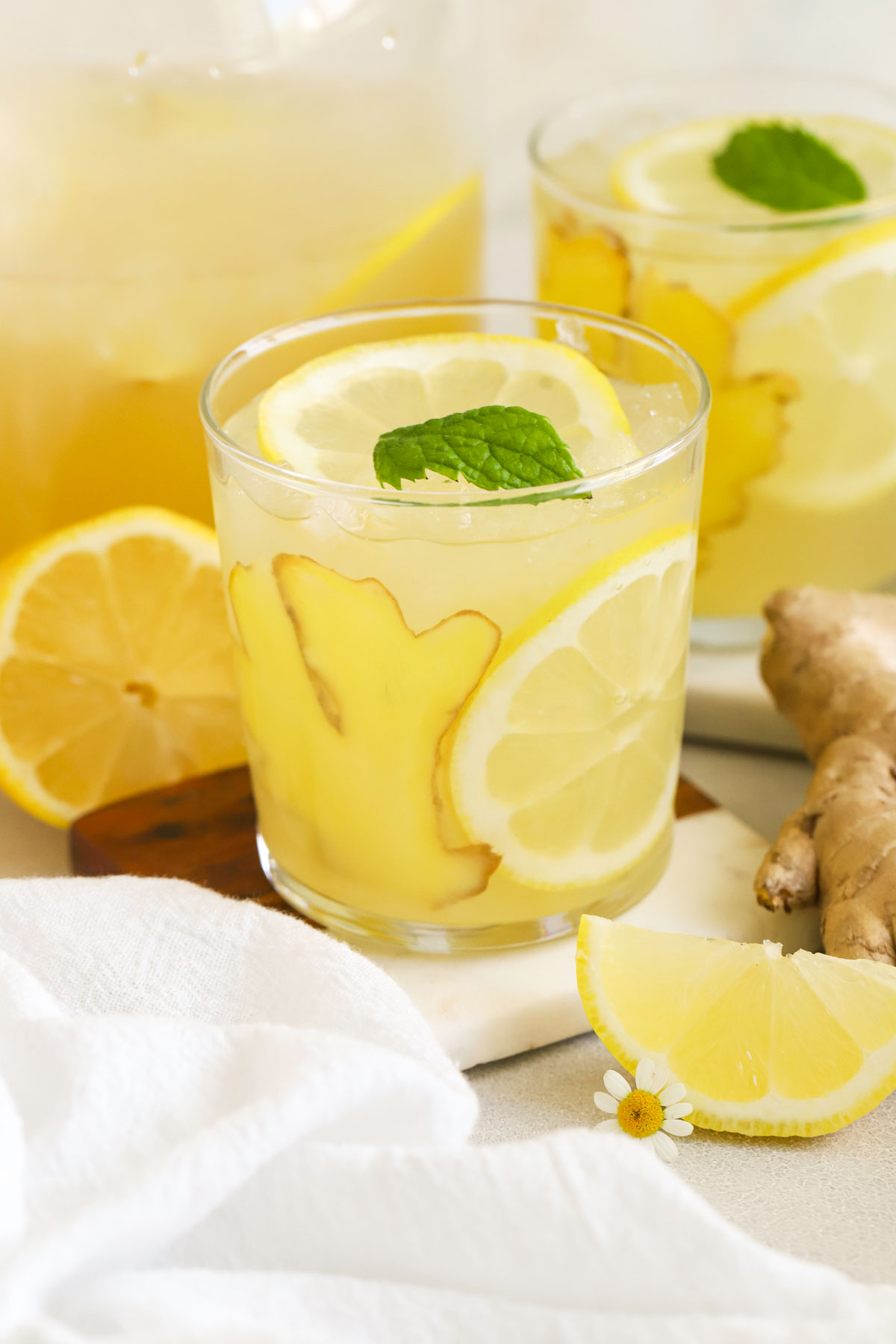 Glasses of honey ginger lemonade garnished with mint, fresh fruit, and slices of ginger