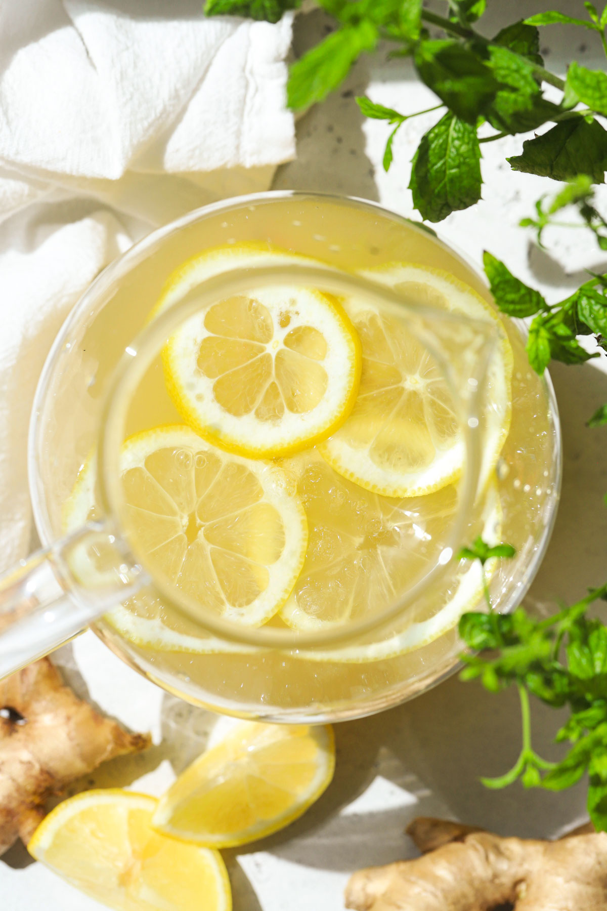 A pitcher of honey ginger lemonade garnished with lemon slices