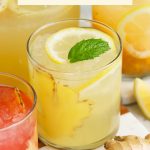 Glasses of honey ginger lemonade garnished with mint, fresh fruit, and slices of ginger
