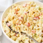 A serving bowl of gluten-free macaroni salad with creamy dressing and colorful veggies