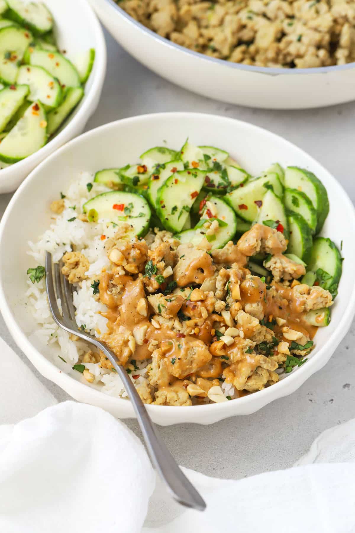 Peanut Chicken Bowls made with seasoned ground chicken, peanut sauce, jasmine rice, cucumber salad, and crushed peanuts