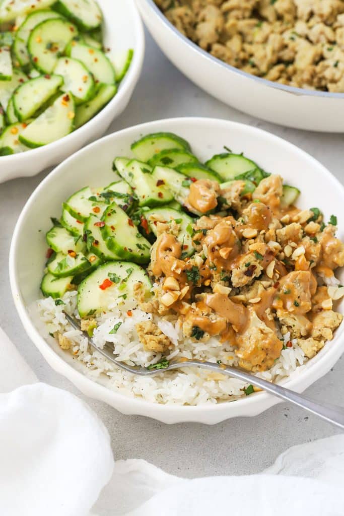 Peanut Chicken Bowls made with seasoned ground chicken, peanut sauce, jasmine rice, cucumber salad, and crushed peanuts