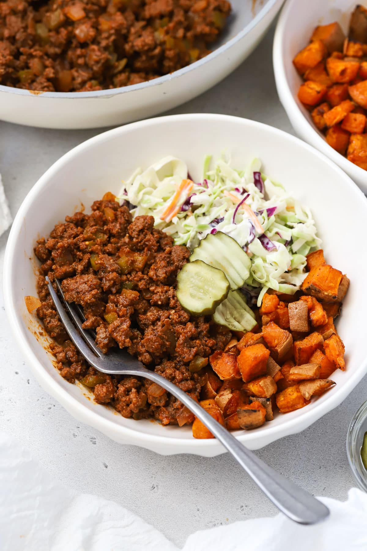 Sloppy joe bowls with sloppy joe beef, roasted sweet potatoes, creamy coleslaw, and dill pickles