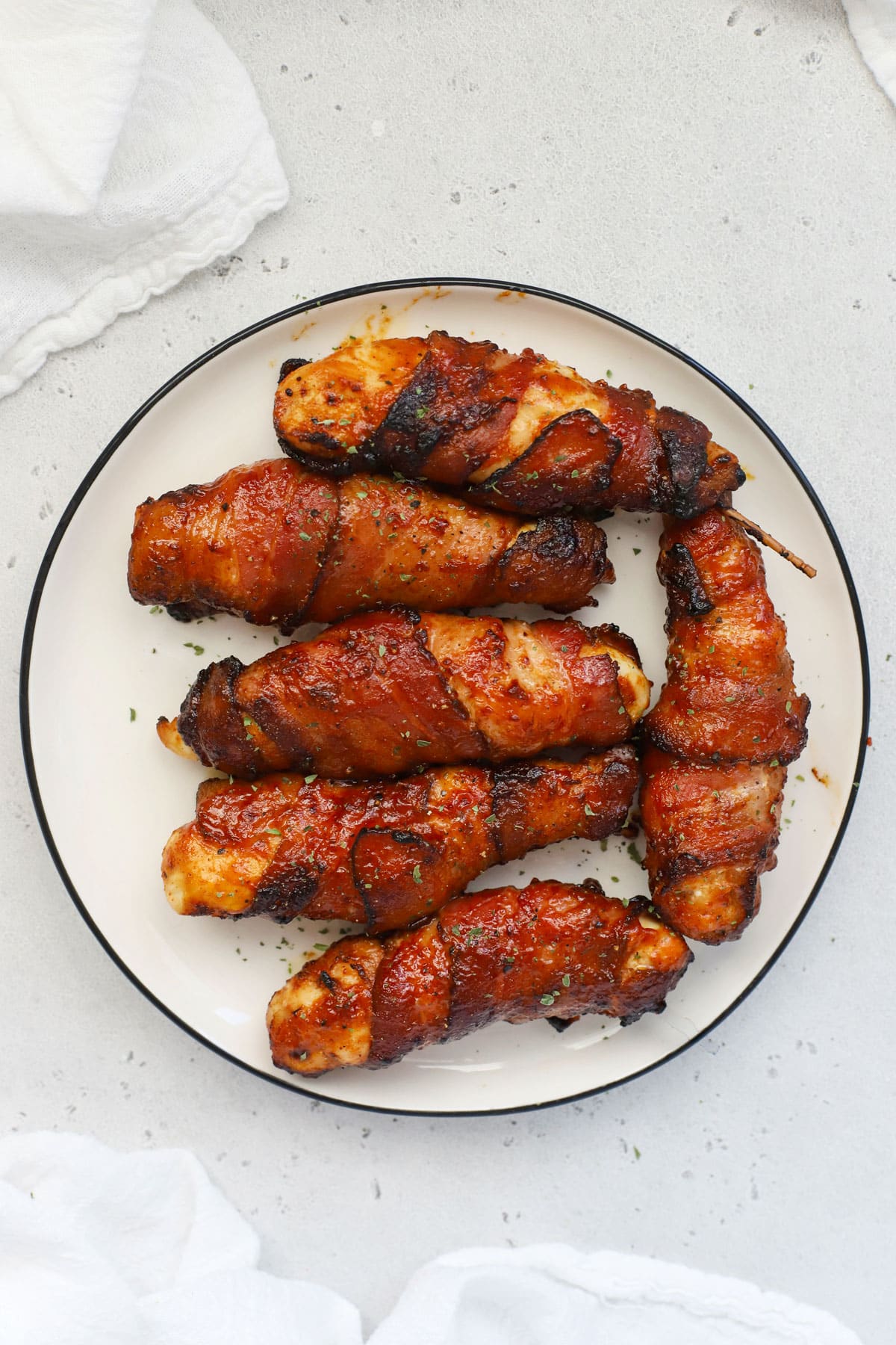 A plate of crispy bacon-wrapped chicken tenders brushed with BBQ sauce