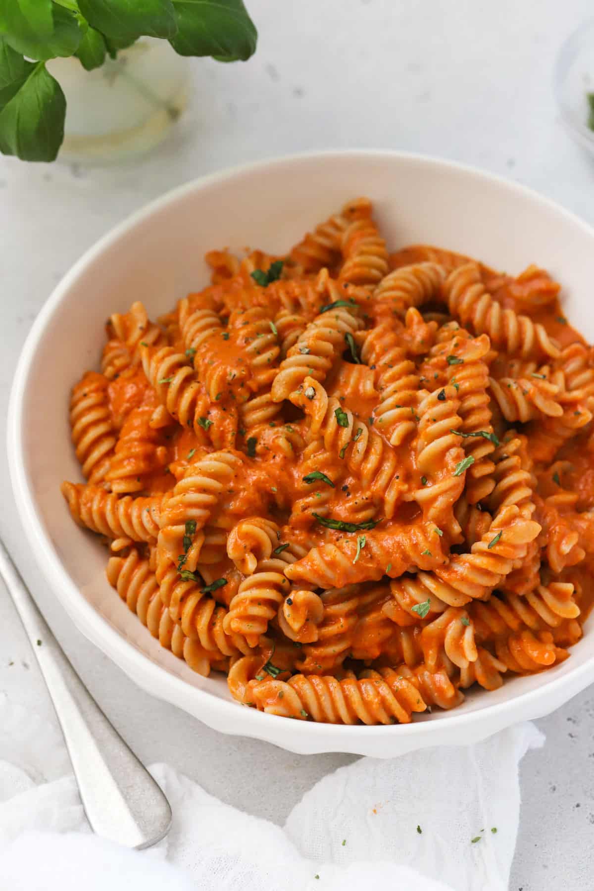 A bowl of pasta with creamy tomato sauce and fresh herbs