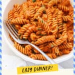 Fork dipping into a bowl of spiral pasta with tomato cream sauce