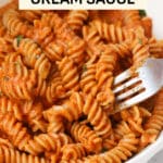Fork dipping into a bowl of spiral pasta with tomato cream sauce