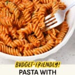 Fork dipping into a bowl of spiral pasta with tomato cream sauce