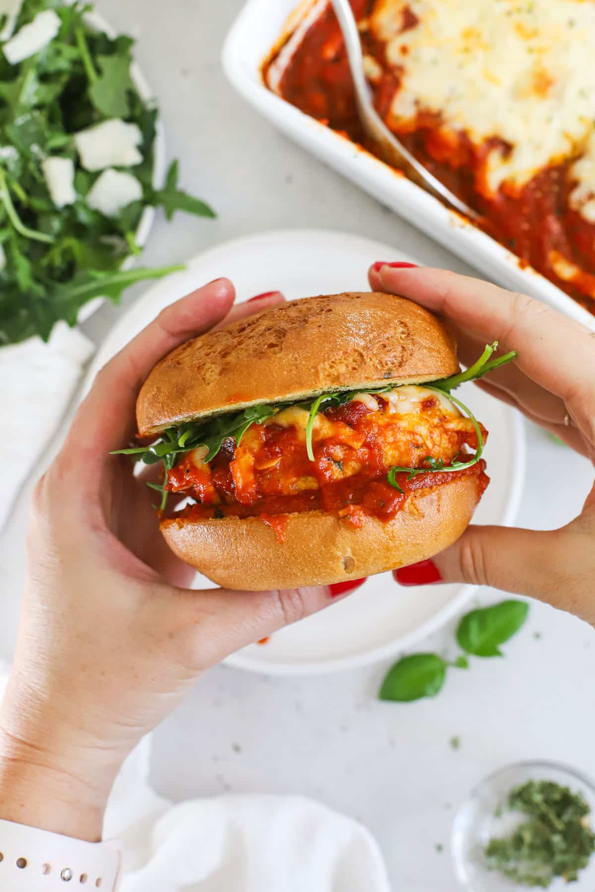 Holding a gluten-free chicken parmesan burger on a toasted gluten-free garlic bread bun