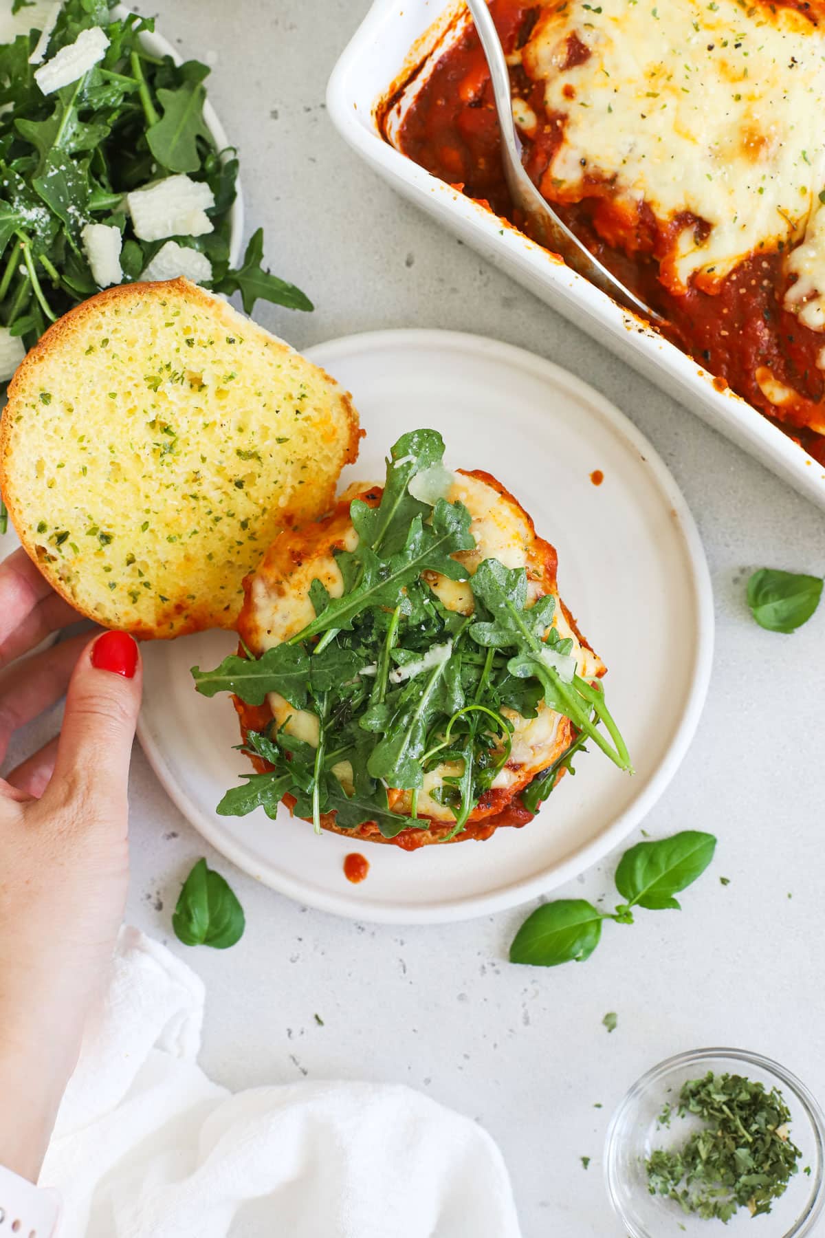 Topping a chicken parmesan burger with arugula salad and a garlic bread bun