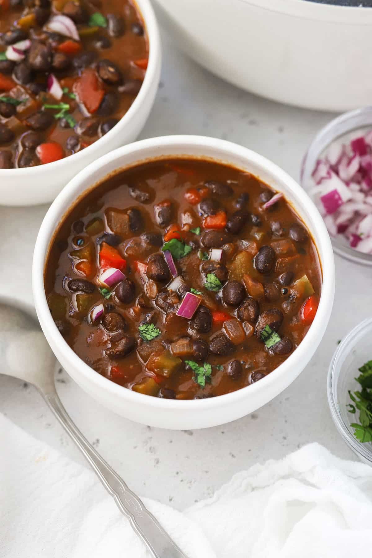 Bowls of Vegan Black Bean Chili garnished with cilantro and red onion