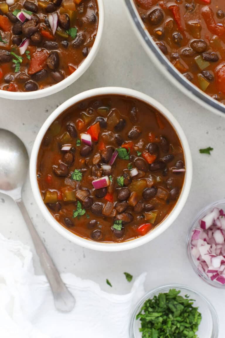 Bowls of Vegetarian Black Bean Chili garnished with cilantro and red onion