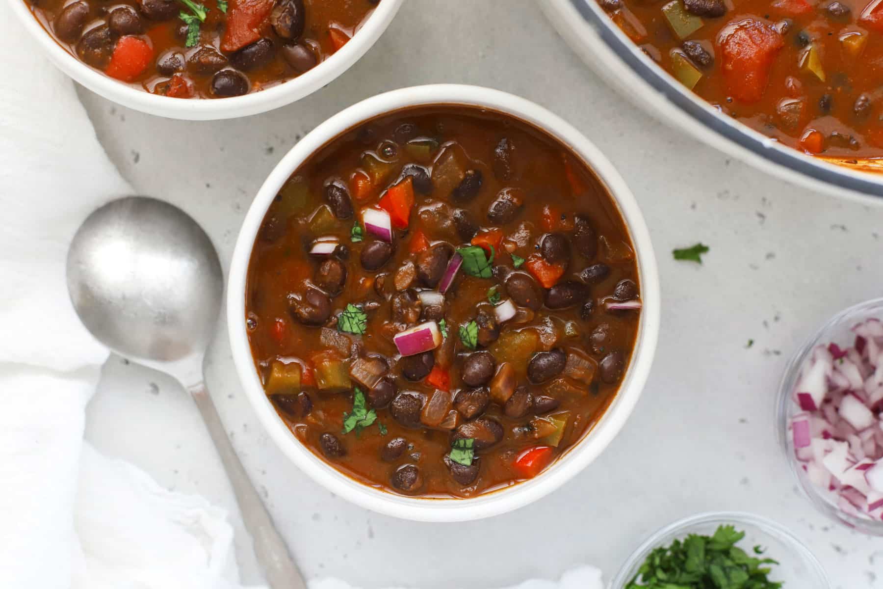 Bowls of Meatless Black Bean Chili garnished with cilantro and red onion