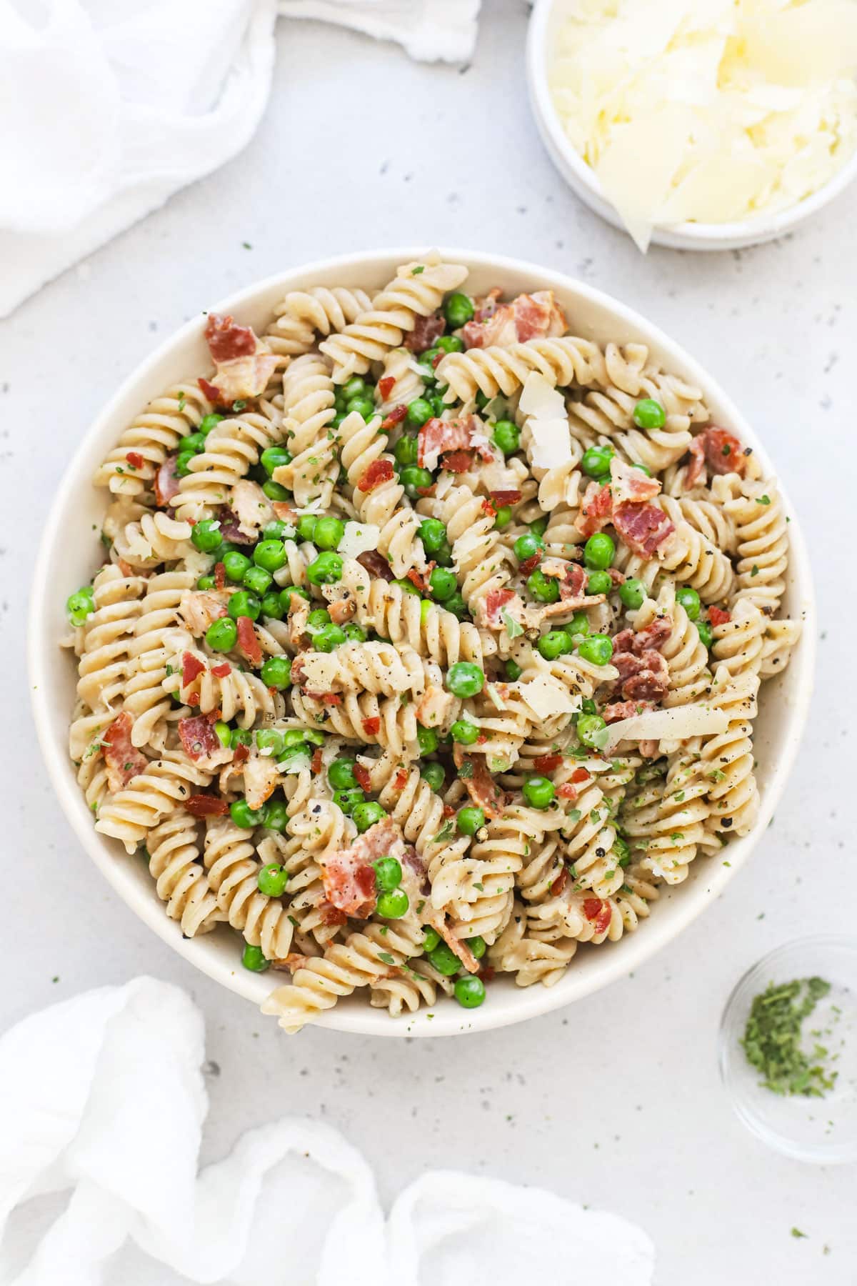 A bowl of parmesan pasta with peas and bacon